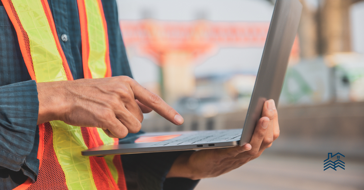 photo shows a contractor wearing a safety vest pressing a button on a computer